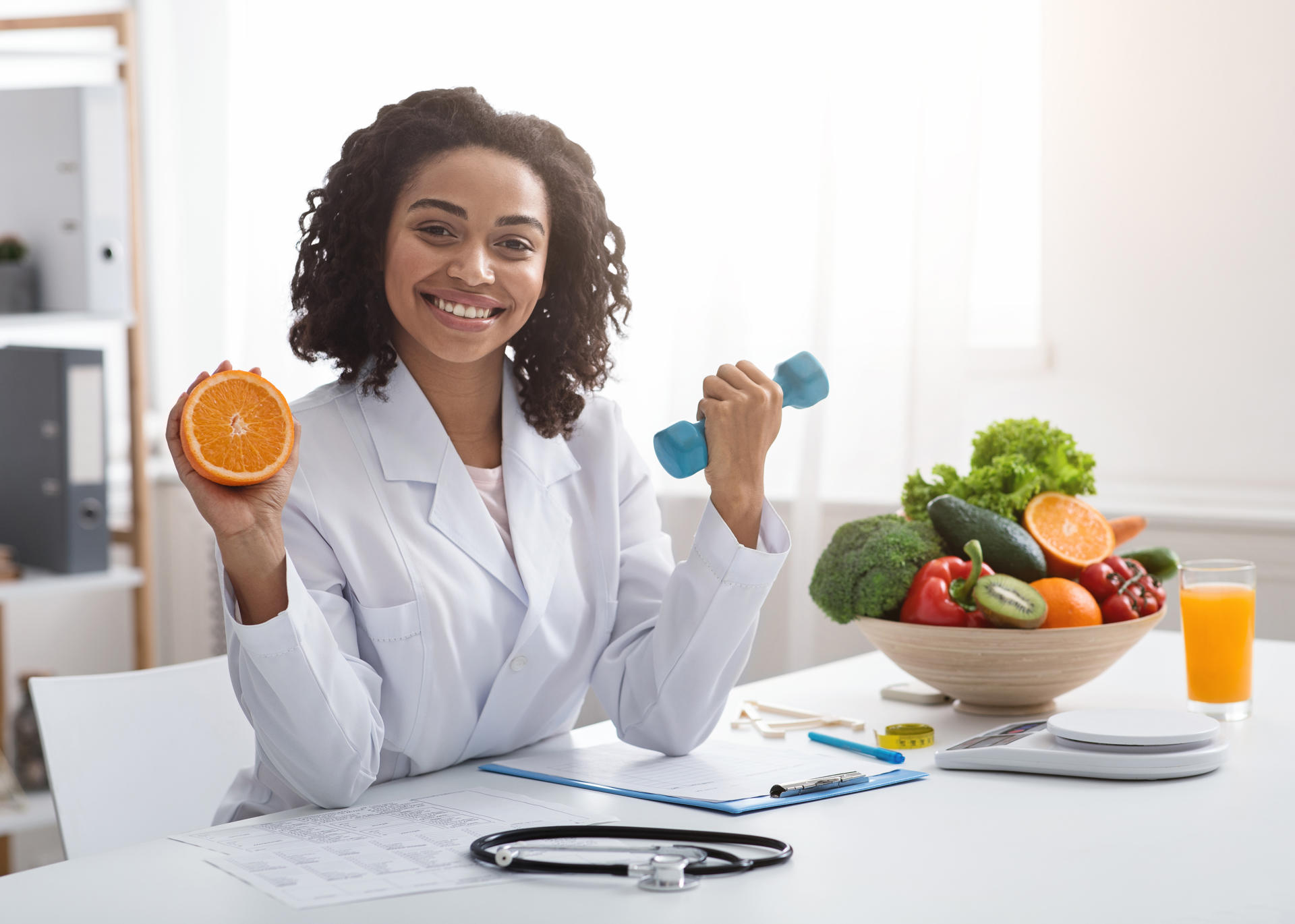 happy-woman-doctor-holding-orange-and-barbell-in-c-2025-03-18-19-27-15-utc.jpg